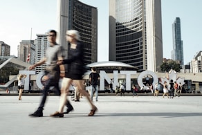 two man and woman walking on pathway near high rise buildings