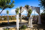 A beautifully decorated wedding arch adorned with white flowers and soft draping fabric.