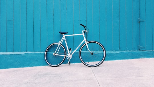 white road bike leaning on teal wooden wall during daytime in Sunset District United States