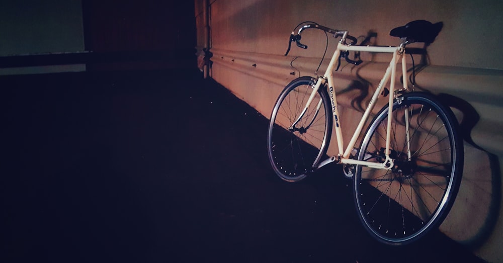 white and black road bike beside white building