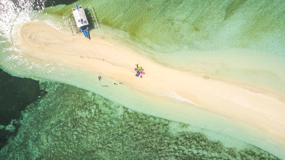 Fotografía aérea de un barco blanco y azul en la orilla del mar durante el día