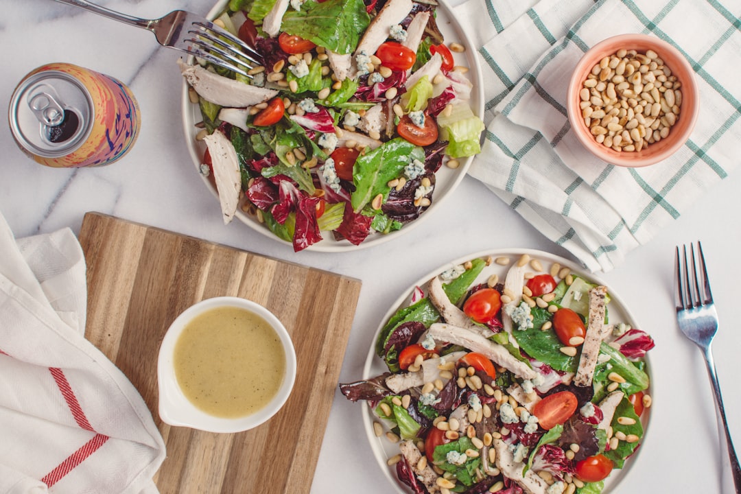 flat lay photography of two bowls of fruit and vegetable salad, Chicken & Pine Nut Salad