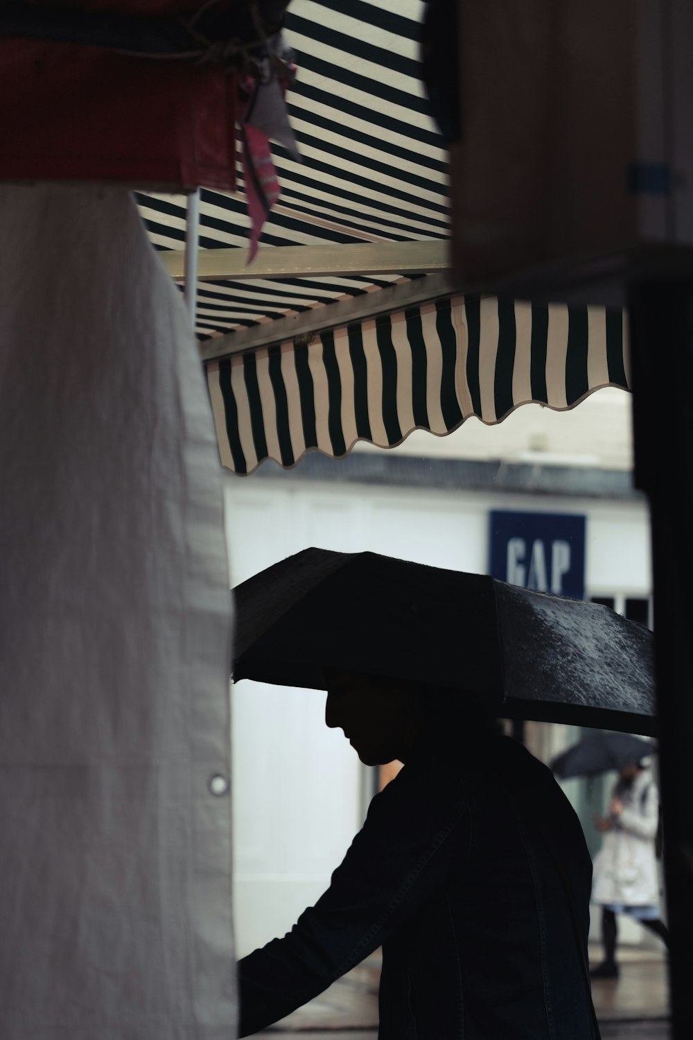 homem usando guarda-chuva sob toldo branco e preto