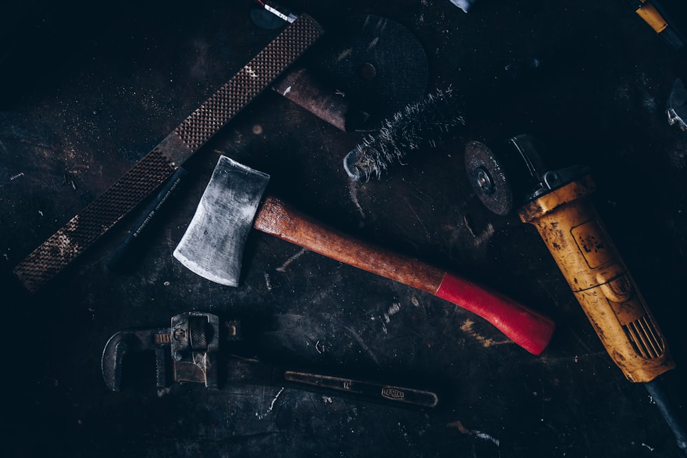 axe beside pipe wrench and angle grinder