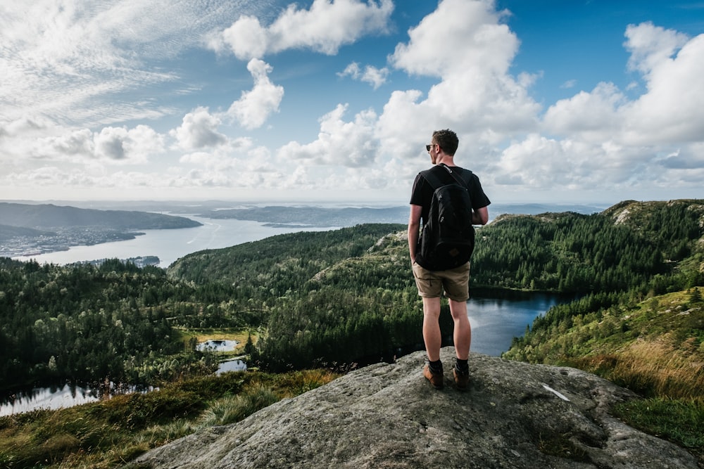 man standing on mountain beside trees