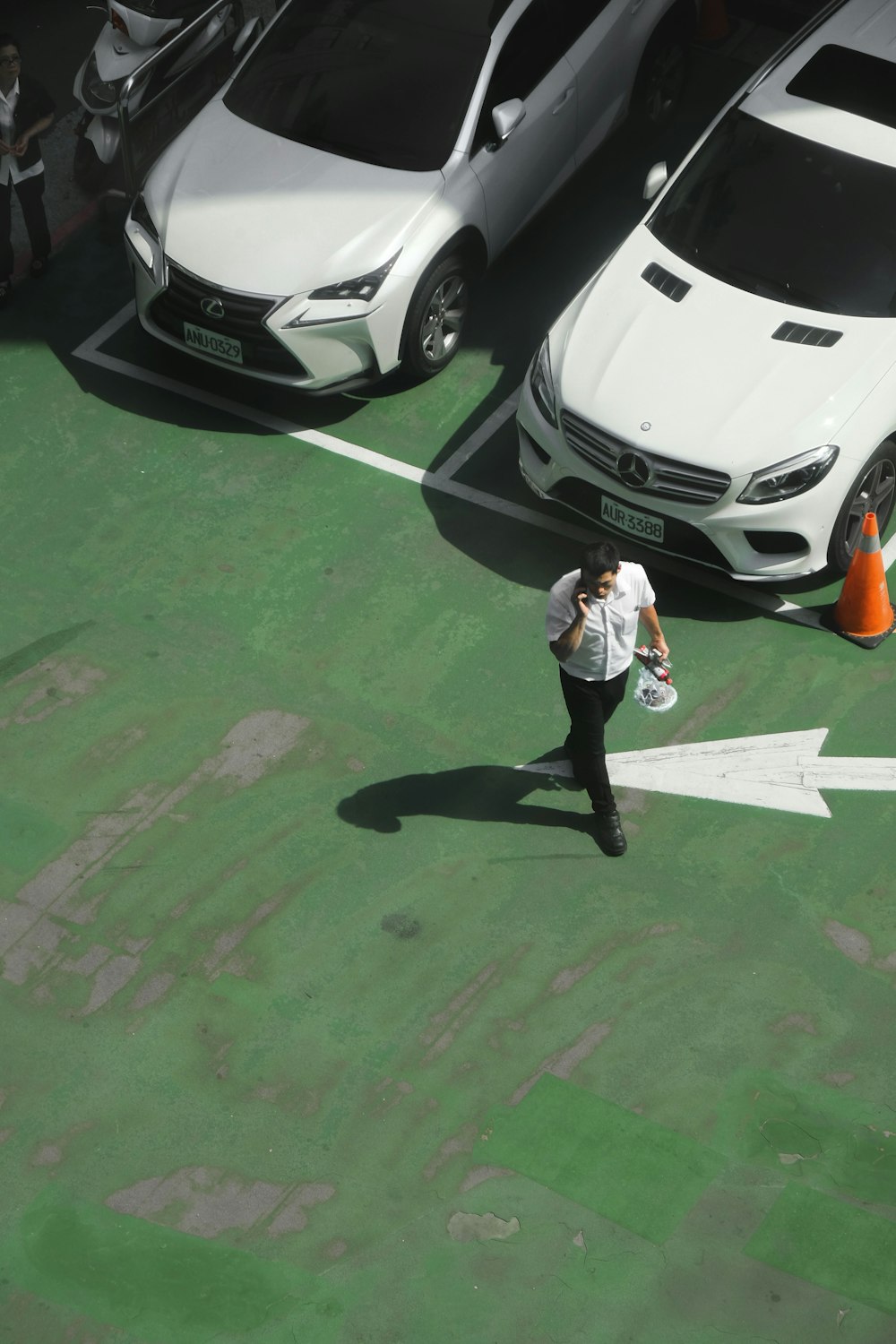 a man walking across a parking lot next to parked cars