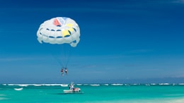 two person riding parachute near beach