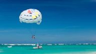 two person riding parachute near beach