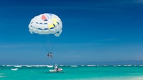 An adventurous group enjoying parasailing over the ocean with a clear blue sky in the background.