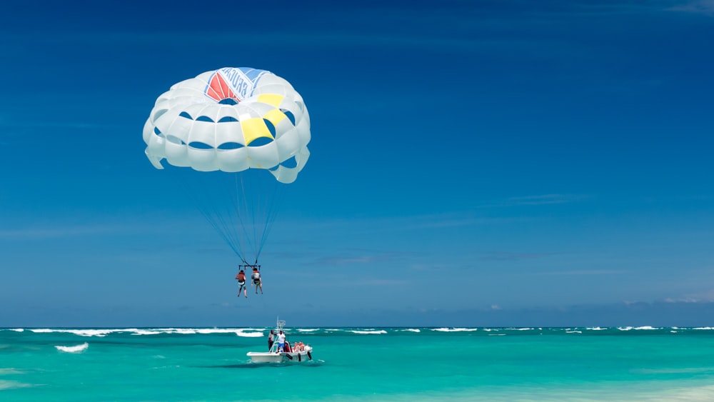 two person riding parachute near beach