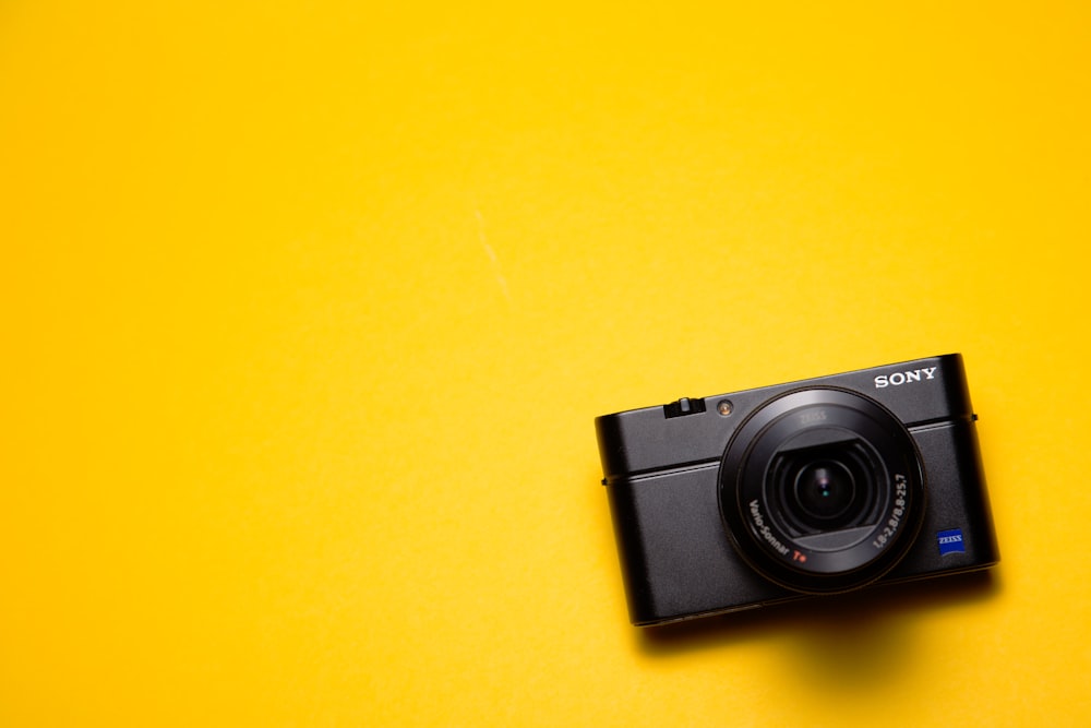 cámara de apuntar y disparar Sony negra sobre superficie amarilla