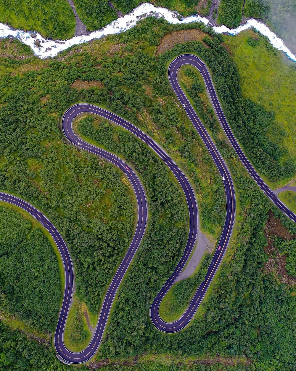 aerial photo of gray concrete roadway near trees during daytime