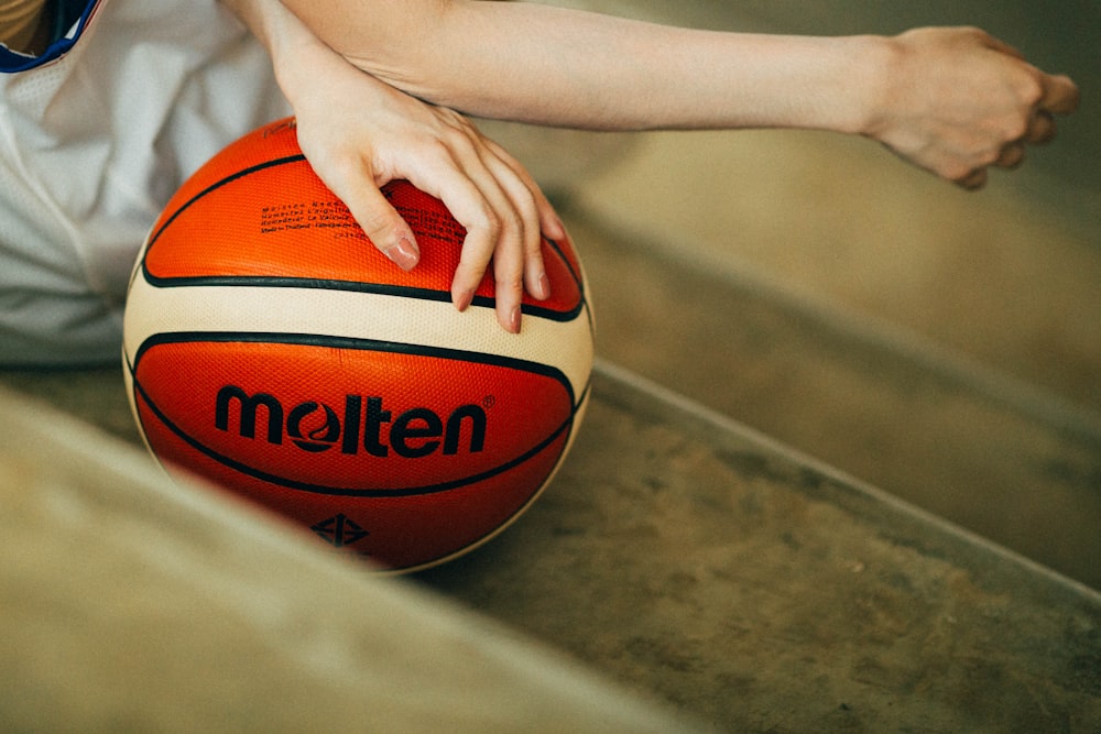person holding red and white Molten basketball ball