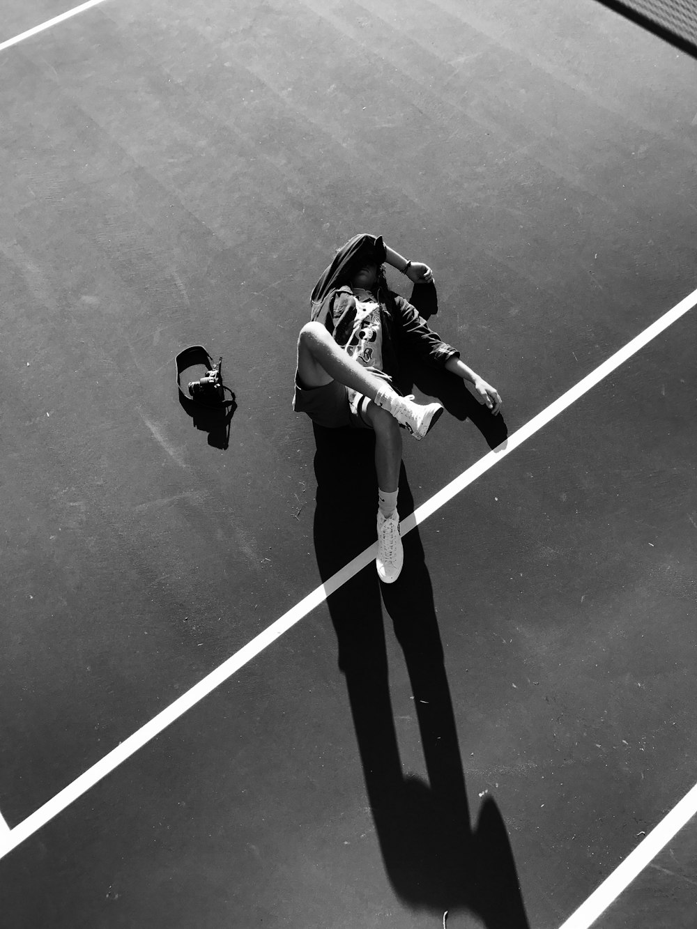 grayscale photo of athlete lying down on court