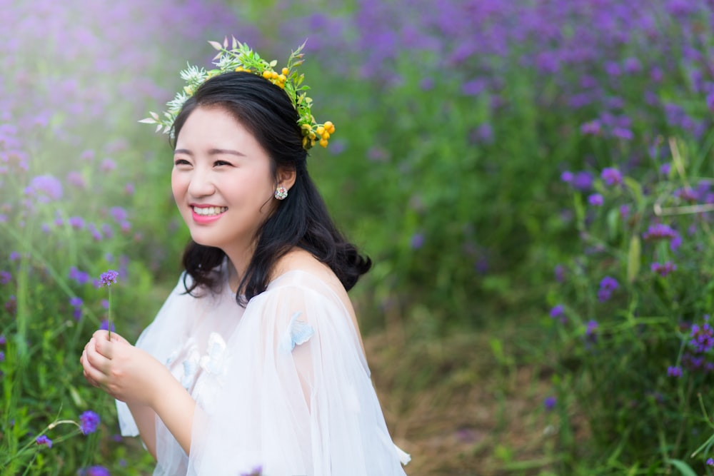 woman wearing white dress holding flower during daytime