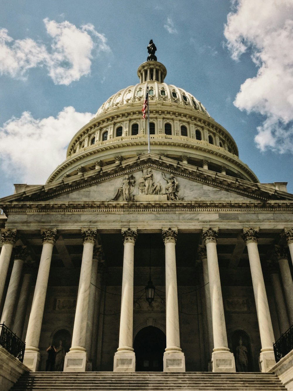 the dome of a building with columns and a flag on top