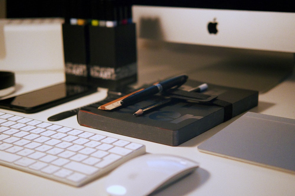 Ratón mágico blanco cerca del teclado de Apple