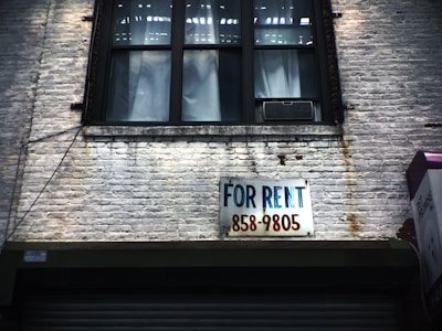 for rent sign on wall below window glass of building