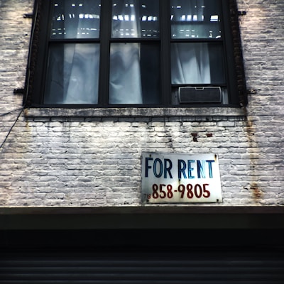 for rent sign on wall below window glass of building