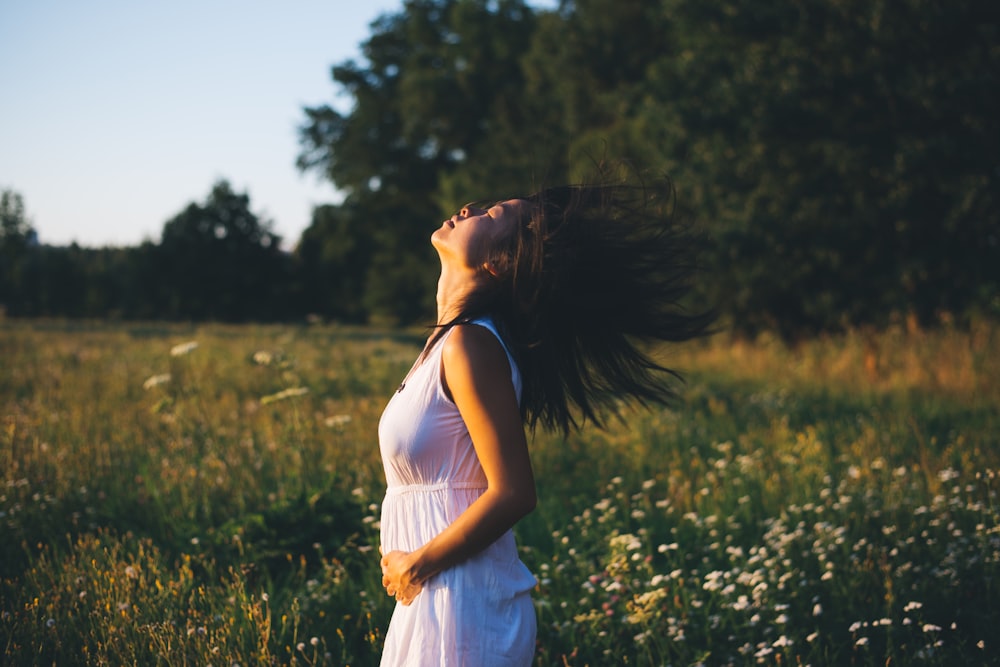 woman wearing white sleeveless dress holding her belly during daytime