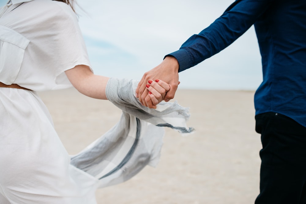 homme et femme se tenant la main dans le champ pendant la journée