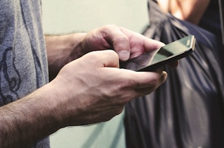 A close-up of a hand holding a smartphone with a contact screen.