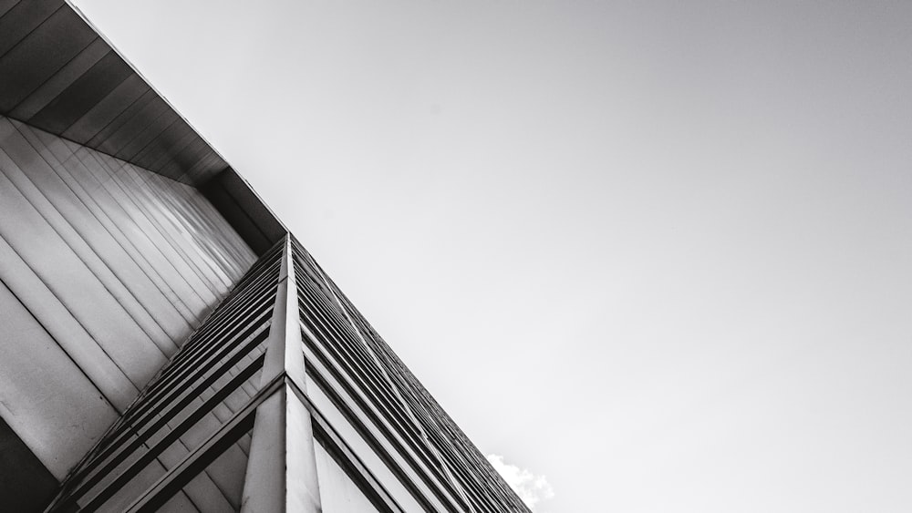 low-angle grayscale photography of building under cloudy sky