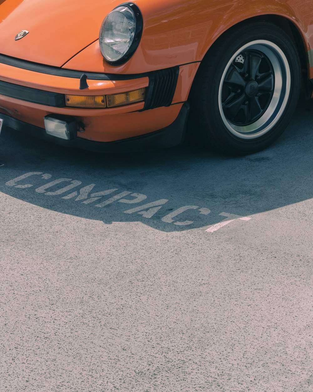 Véhicule Porsche orange sur le parking Compact