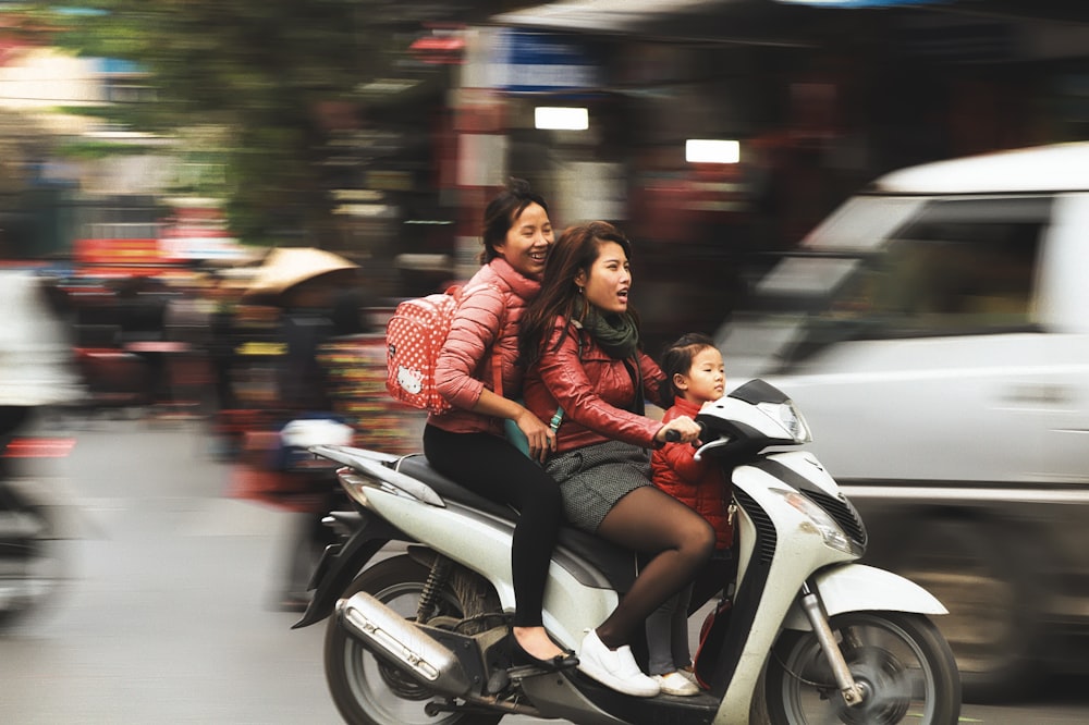 Selektive Farbfotografie einer Frau, die einen weißen Motorroller fährt