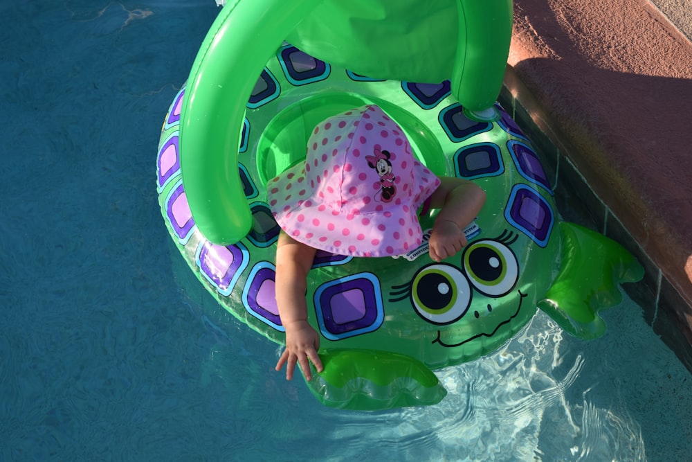 toddler riding on blue floating buoy during daytime