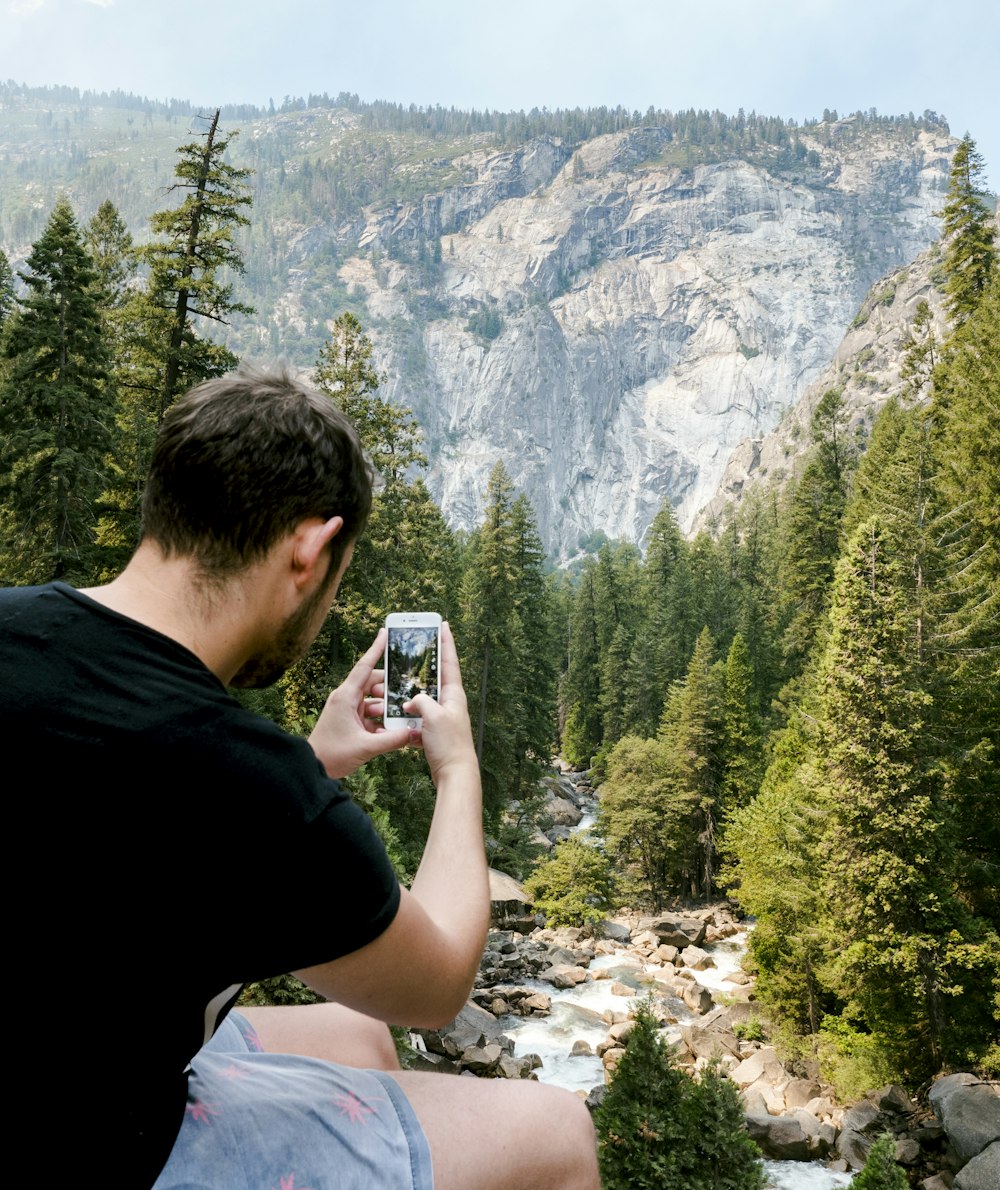 man holding white smartphone capturing tree