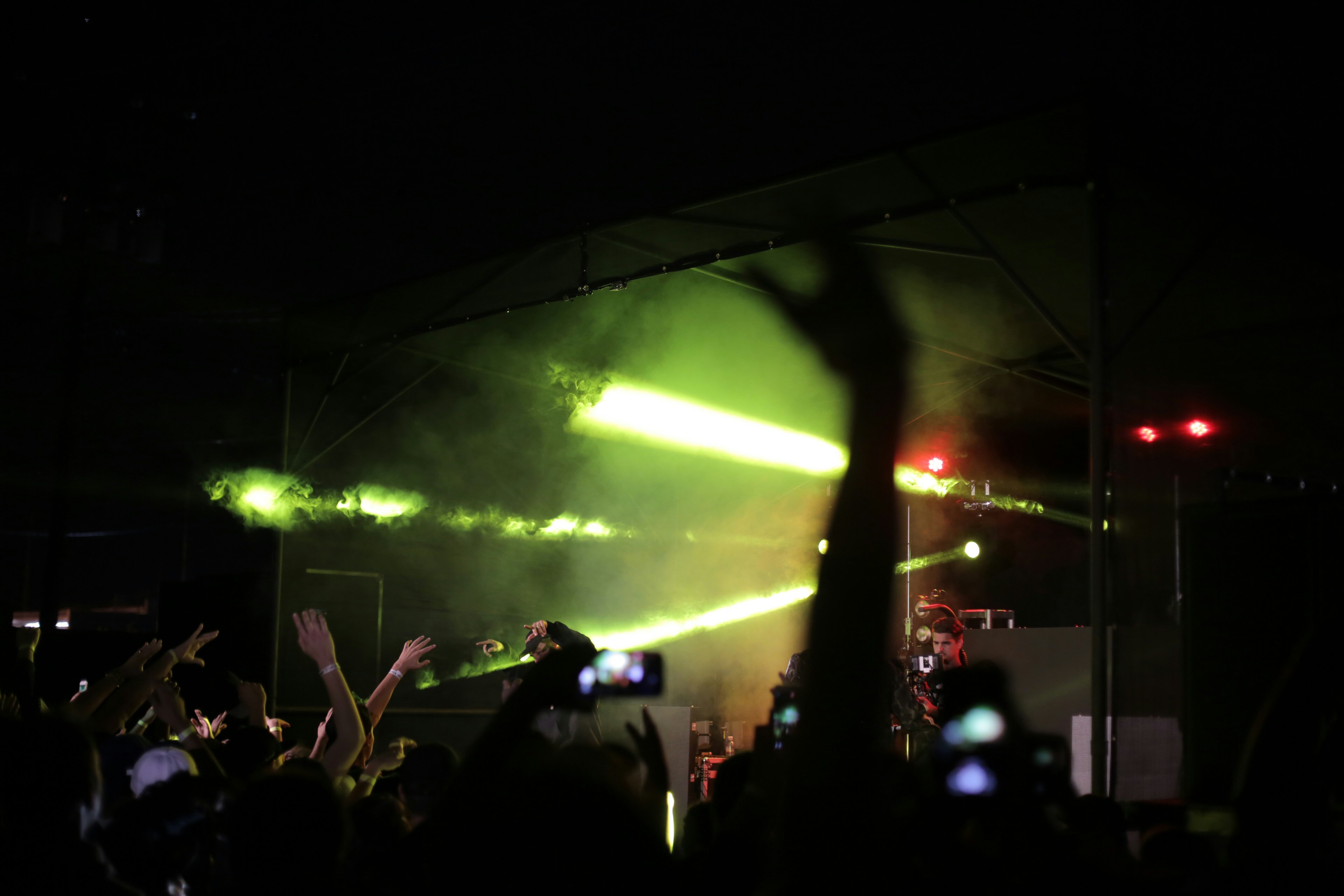silhouette of crowd raising hands fronting concert stage