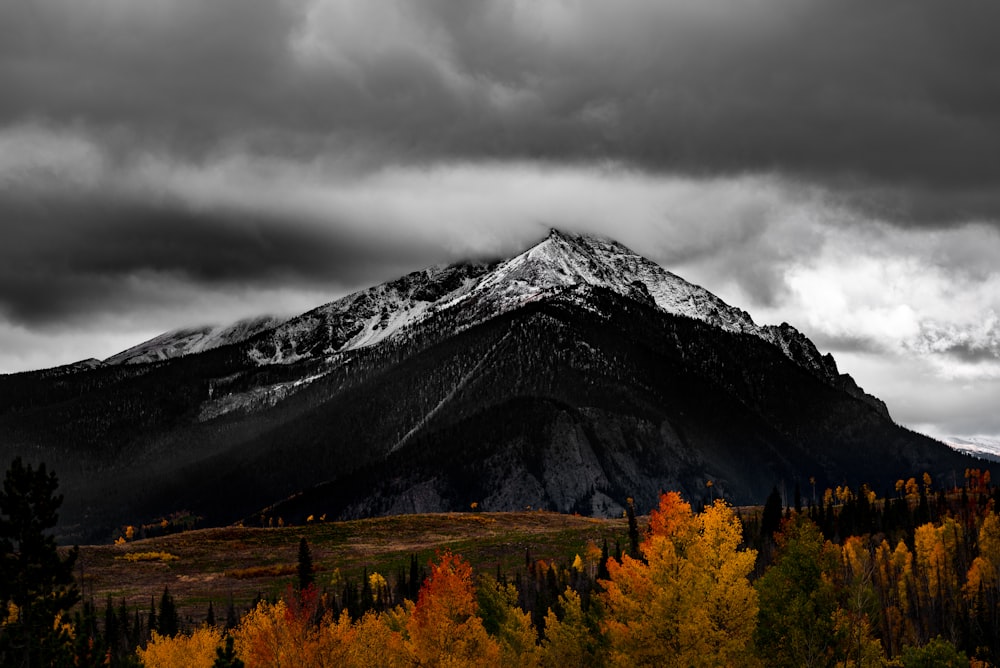 black mountain near trees under cloudy sky