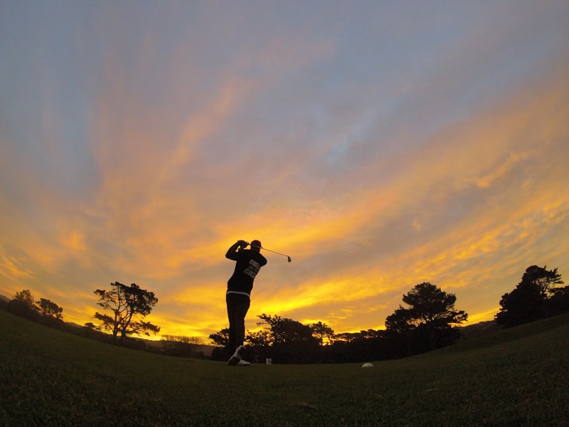 Silhouette gripping a golf club at sunset