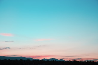 A serene landscape of rolling hills under a colorful sunset.