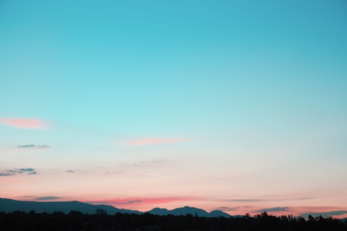 A serene landscape of rolling hills under a colorful sunset.