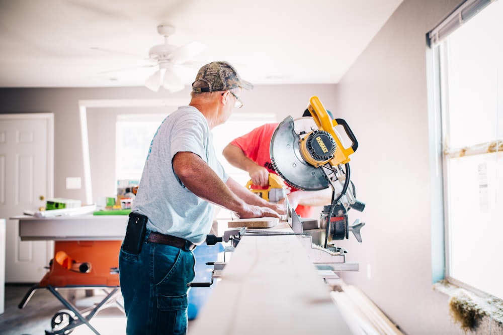 A carpenter with a camoflauge hat using a table saw