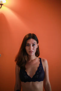 A sunny yellow lace camisole hanging against a colorful wall with warm lighting.