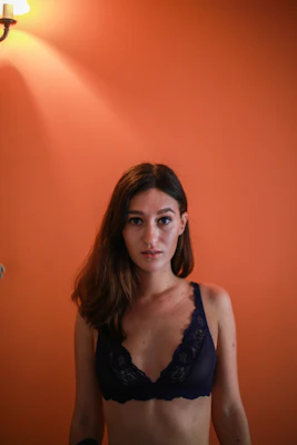 A sunny yellow lace camisole hanging against a colorful wall with warm lighting.