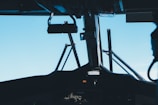 The interior view of an aircraft cockpit, showcasing various controls and instruments with a clear blue sky visible through the windows.