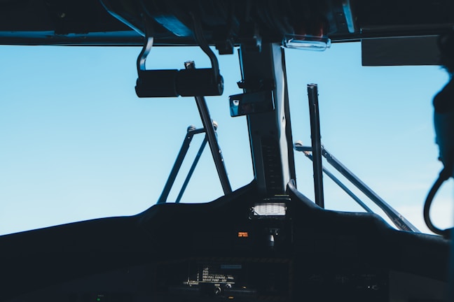 The interior view of an aircraft cockpit, showcasing various controls and instruments with a clear blue sky visible through the windows.