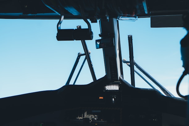 Close-up of a pilot's hands adjusting flight controls inside a cockpit with clear blue skies outside.