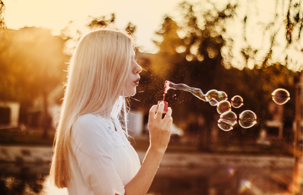 femme soufflant des bulles au coucher du soleil