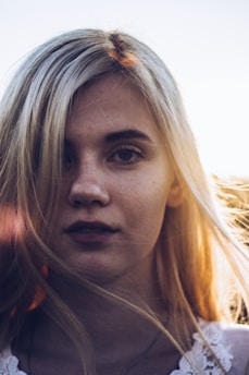 A close-up portrait of a person bathed in soft golden hour sunlight on a beach.