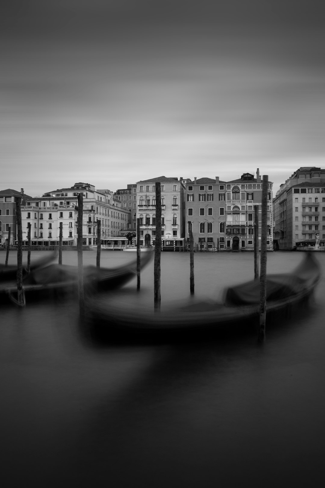 grayscale photography of two canoe in front of city buildings