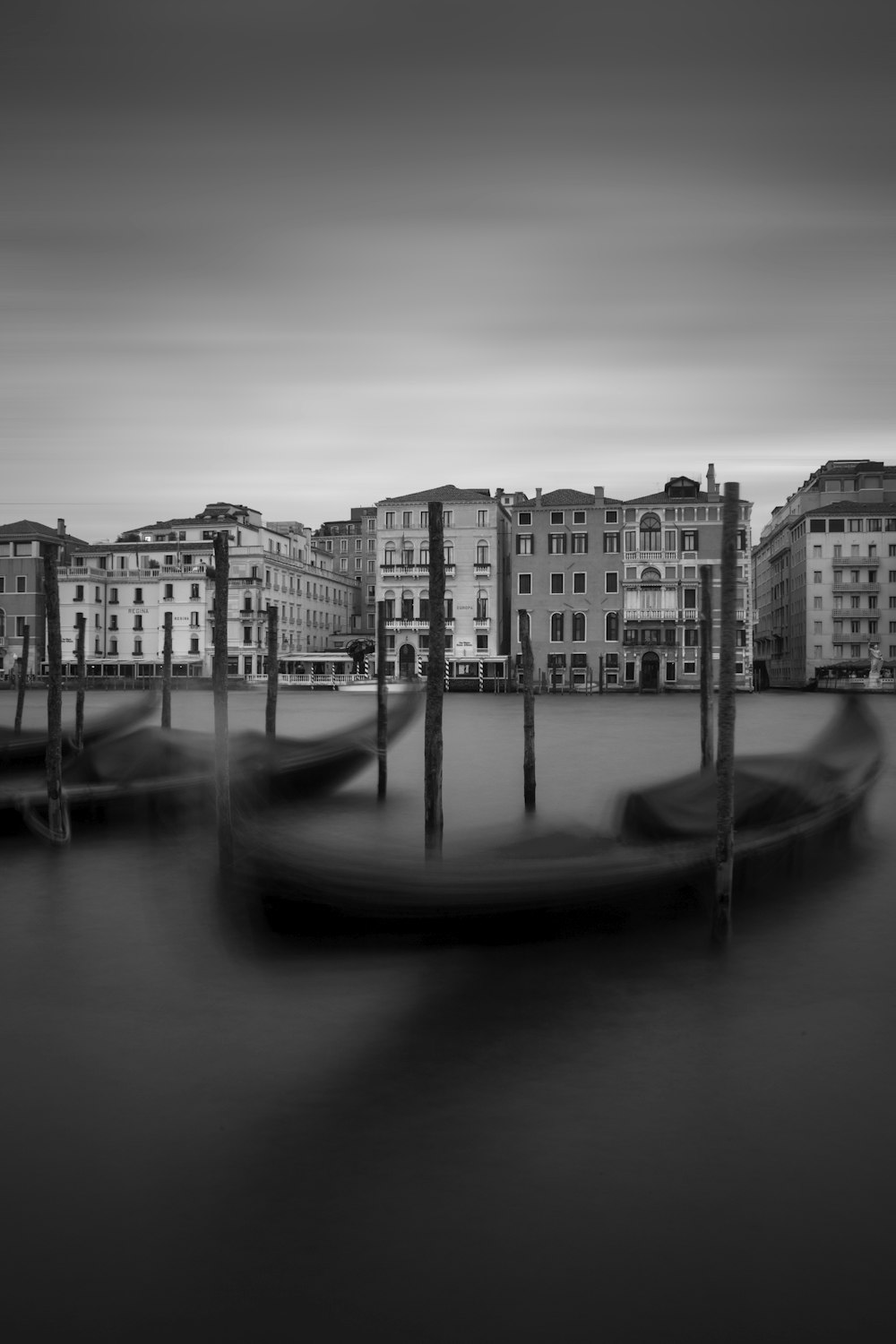 grayscale photography of two canoe in front of city buildings