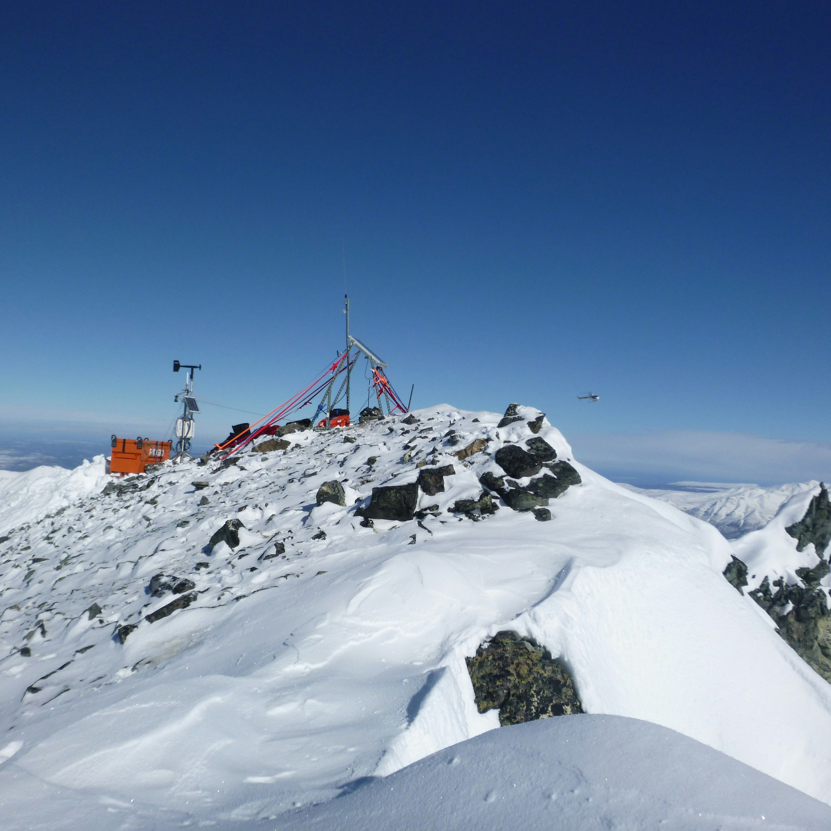 Elite expedition team with advanced detection equipment exploring remote mountain terrain with helicopter in background