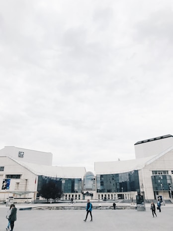 A modern corporate campus building with employees walking outside on a sunny day.