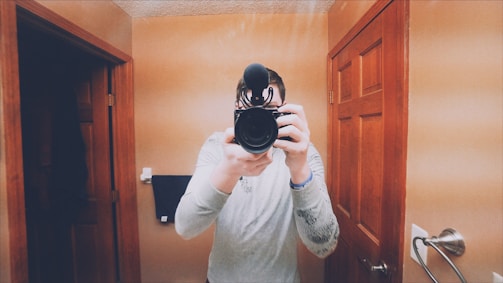A creator filming a grooming routine video in a bright, modern bathroom.