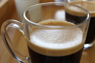 Close-up of a rich, creamy toffee coffee being poured into a clear glass mug.